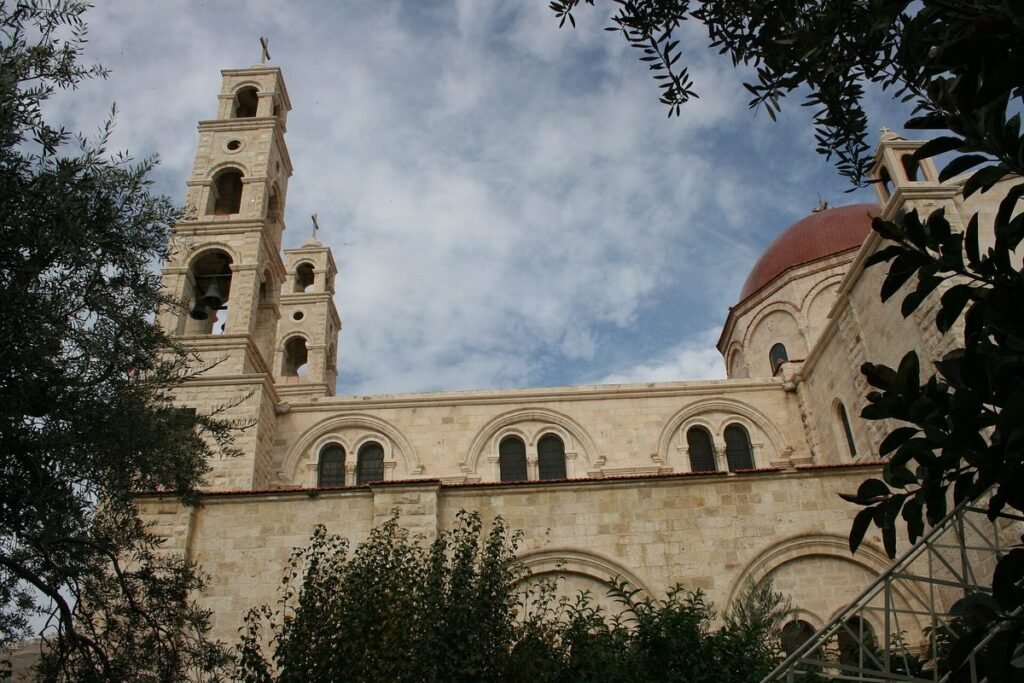 Kirche mit Glockentürmen und Kuppel am Jakobsbrunnen, zwischen Zweigen gesehen
